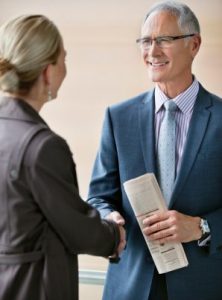Two people shaking hands before a meeting
