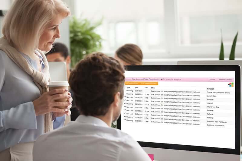 Woman and man in office setting looking a a computer screen that shows the Rosemark System home care management software