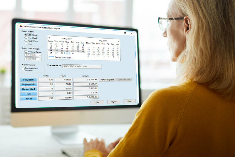 A woman reviewing Rosemark System reports on her computer to improve caregiver management and scheduling