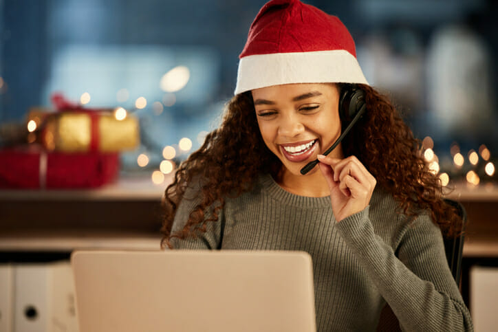 A woman wearing a Santa hat looking at her computer to learn more about home care agency growth