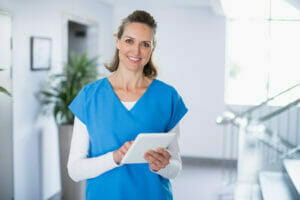 Caregiver with tablet using caregiver mobile app to clock in to her shift