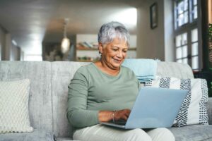 A senior woman looking at a home care website on her personal computer as she sits on her sofa