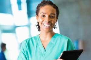 Woman in scrubs holding a tablet so she can access her home care management system