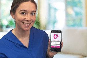 Caregiver holding a mobile phone with the Rosemark System caregiver mobile app on the screen