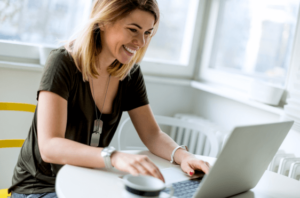 Happy, smiling woman working on her computer to learn more about her home care software