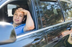 Home care agency caregiver experiencing caregiver burnout, looks exhausted sitting in her car staring out the window