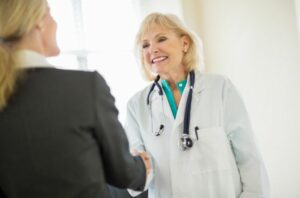 Marketer and social worker shaking hands with a doctor to help build a relationship to get client referrals