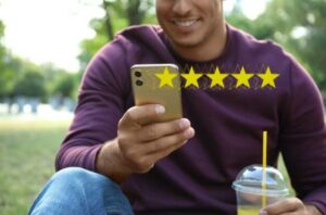 Man in a purple shirt holding a cell phone that is superimposed with 5 yellow stars showing he provided a positive business review