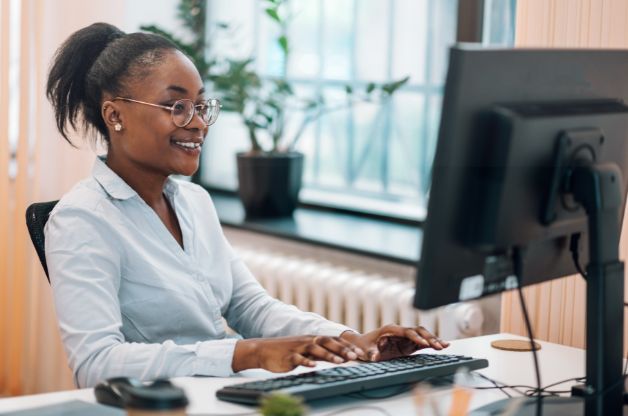 A smiling home care administrator using a computer to streamline home care referral management and reduce administrative tasks.
